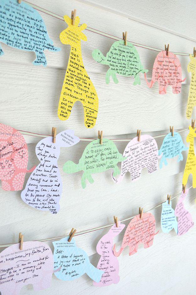 DIY baby shower decoration wishes for baby cards, pastel paper elephants giraffes and turtles pegged along cords