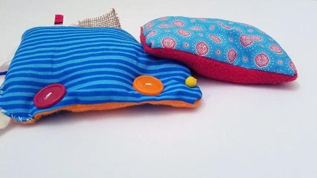 DIY sensory toy, two small fabric cushions in blue stripe and teal paisley print with purple and orange buttons sewn on
