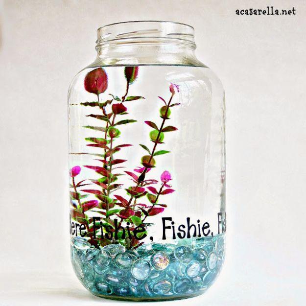 DIY aquarium in a gallon pickle jar with red and green plants, blue glass pebbles and vinyl lettering on the glass