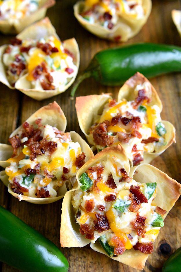 Jalapeno popper wonton cups baked in a muffin tin with creamy cheese and bacon filling on a platter ready for a party