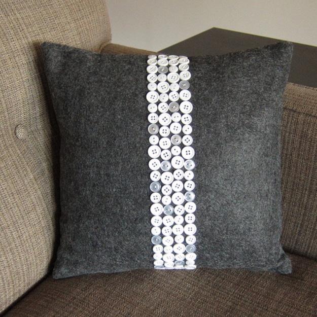 Button pillow, a dark grey felt cushion with a wide vertical stripe of white buttons sewn down the centre front