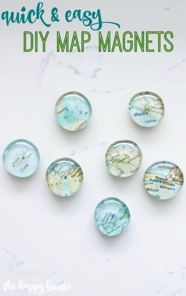 Quick and easy DIY map magnets, seven flat glass rocks with map pieces glued underneath arranged on a white marble surface