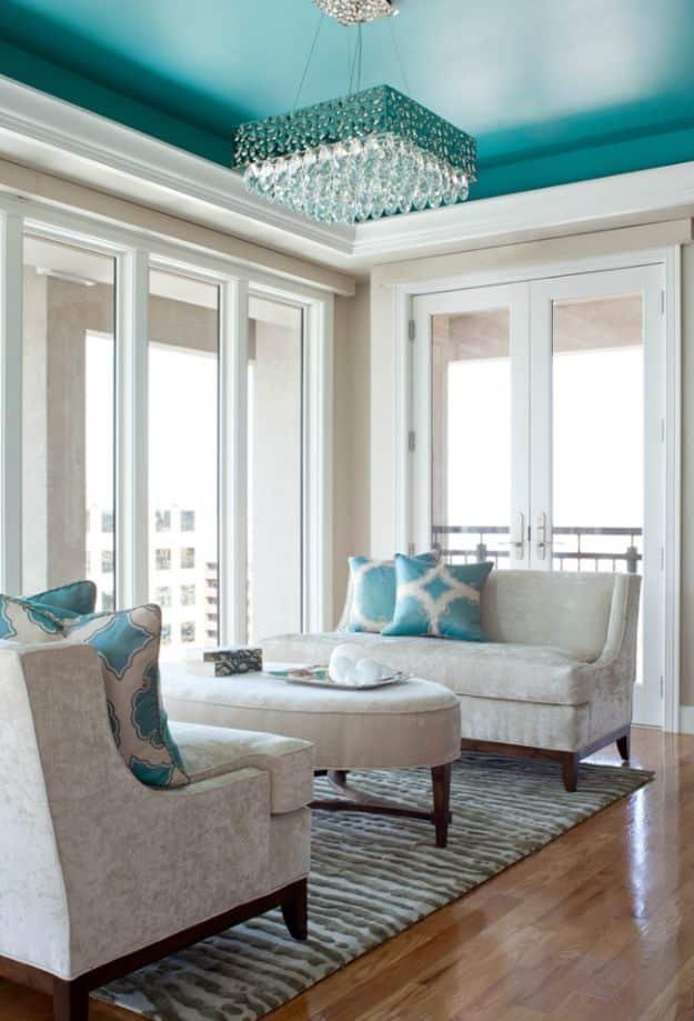 Modern living room with a recessed ceiling painted turquoise above a crystal chandelier and neutral seating