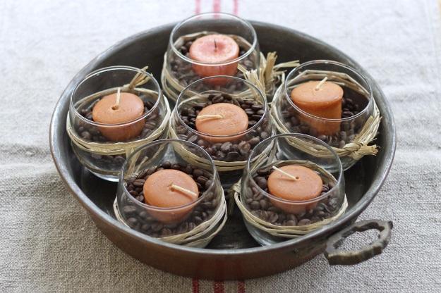 Coffee bean centerpiece with round glass vases filled with beans, wrapped in raffia and holding lit votive candles
