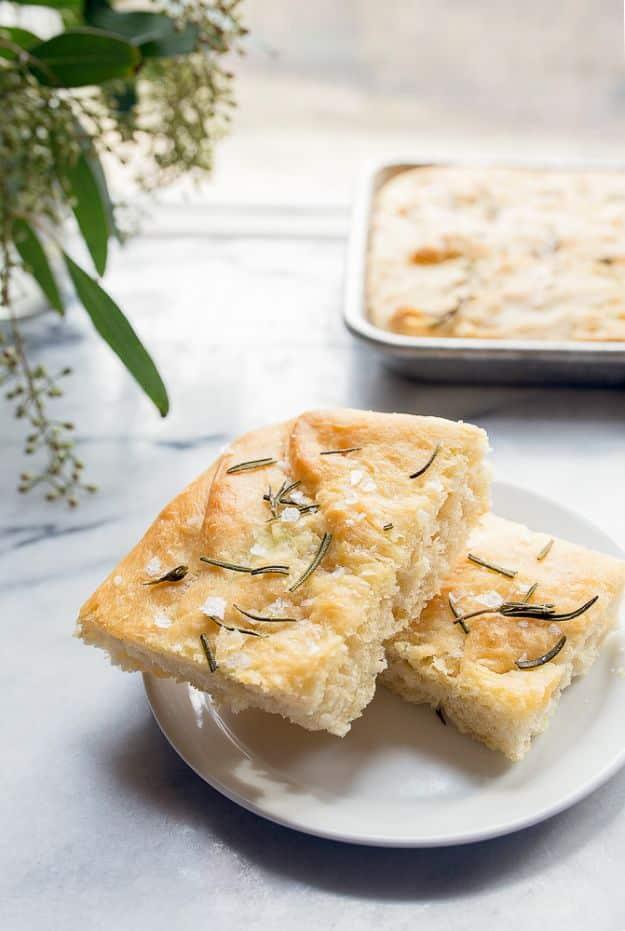 Small batch rosemary focaccia dimpled with fingertips, baked golden in olive oil with coarse salt on top