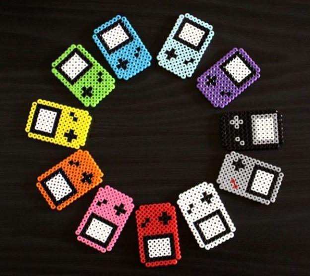 Perler beads GameBoy fridge magnets, a ring of handheld console shaped bead magnets in rainbow colors on black