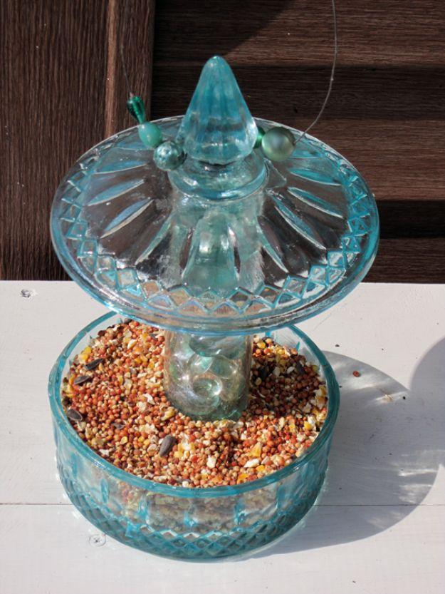Aqua painted candy jar bird feeder, a cut glass lid with a pointed finial above the seed filled jar on a clear glass base