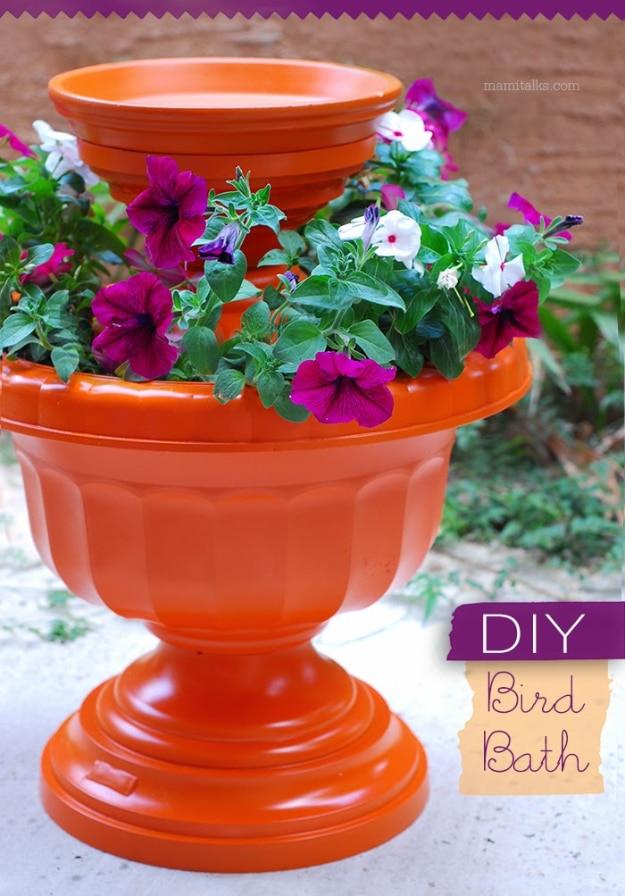 DIY curb appeal bird bath made from stacked orange painted urns and a saucer planted with purple and white petunias