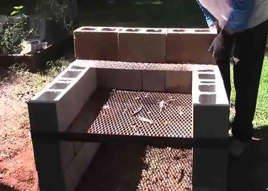 Finished DIY backyard cinder block grill with the metal mesh cooking surface and a small shelf on the top level