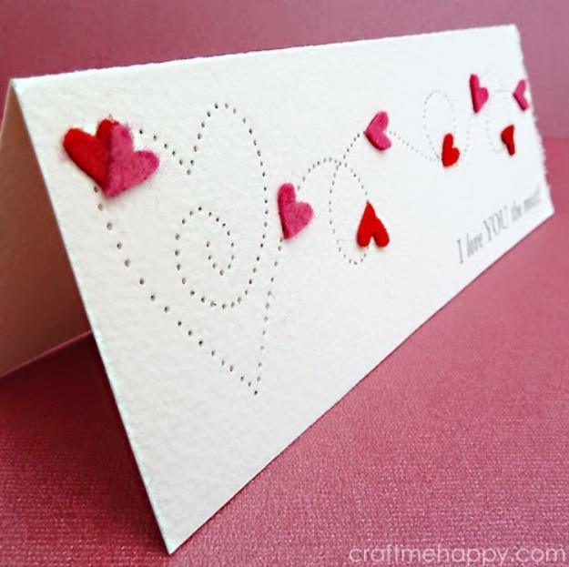Paper pierced Valentine's card with rows of tiny punched holes tracing a heart and swirl on watercolor board
