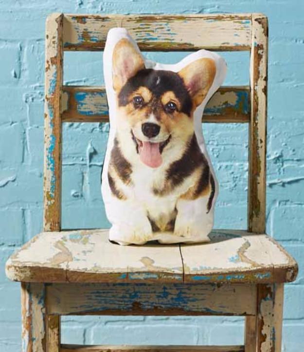 A white cotton pillow printed with a dog's face, propped on a sofa beside the real dog, a personalized Etsy listing