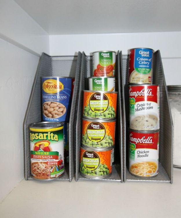 Three grey mesh magazine racks on a pantry shelf holding stacked soup, bean and tomato cans on their sides