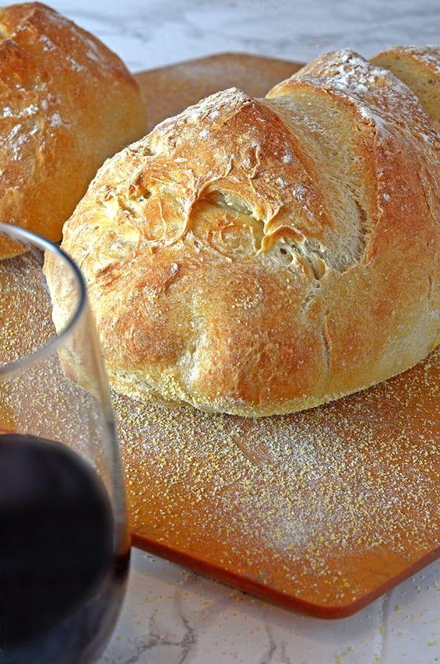 Homemade crusty bread with three deep slashes across a golden brown loaf baked on a hot baking stone