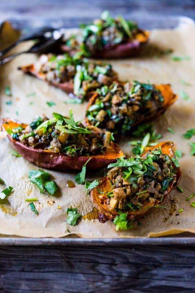 Moroccan stuffed sweet potato halves topped with spiced chickpeas, herbs and green sauce on a parchment tray