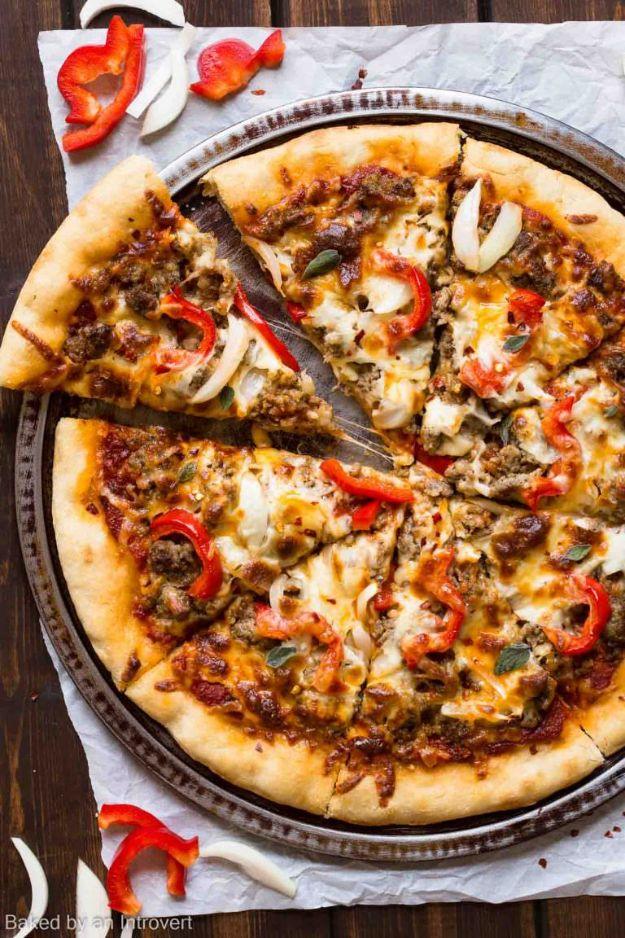 Spicy sausage pizza on a round pan with sweet peppers and onion over melted mozzarella, one slice cut
