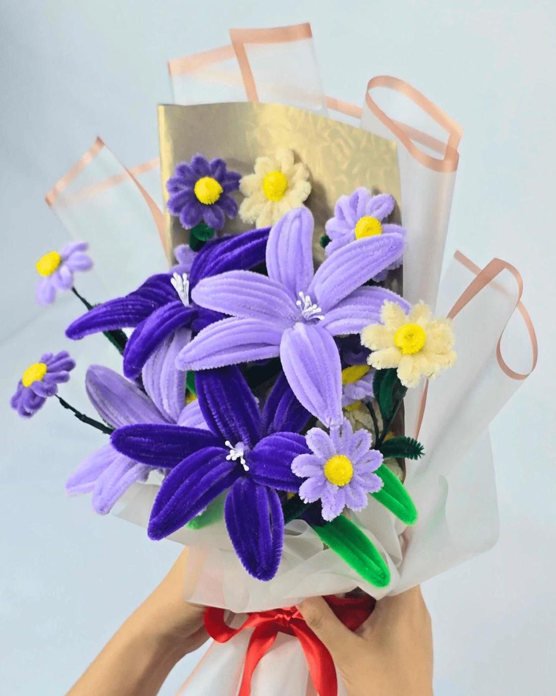 A violet pipe cleaner flower bouquet of handmade daisies and lilies arranged together in a vase for home decor