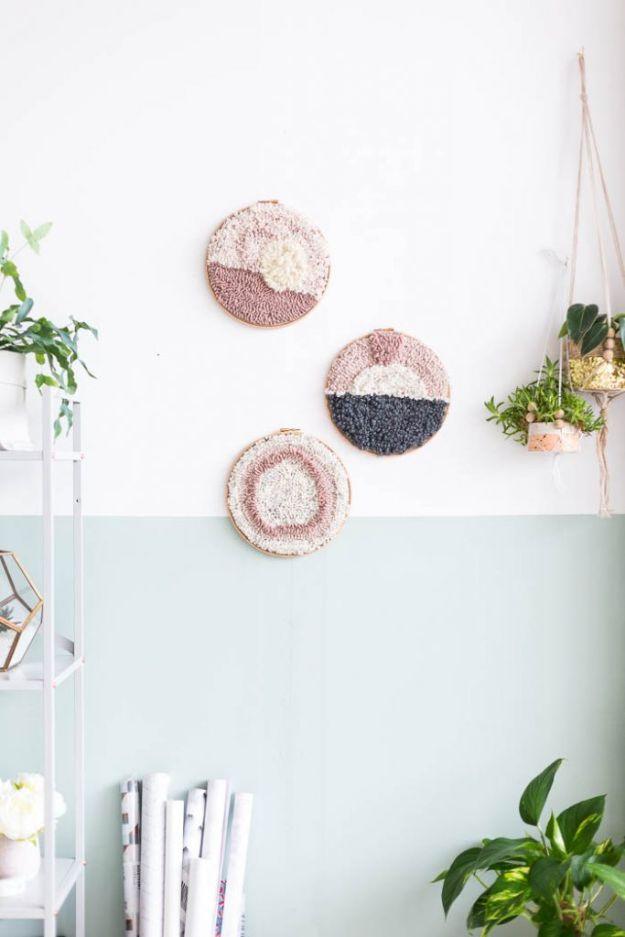 Three round punch needle hoop artworks in pink and cream hung on a two tone wall, a beginner DIY decor idea