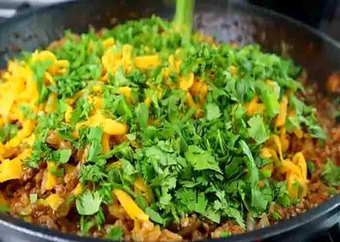 Adding the ingredients to make the taco rice