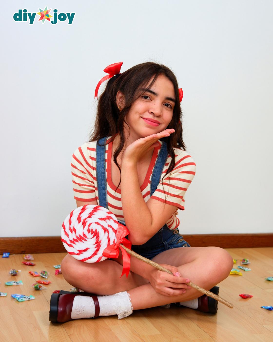 Easy Halloween Costumes - the candy girl seated on the floor in her striped shirt, the swirl lollipop leaning beside her.