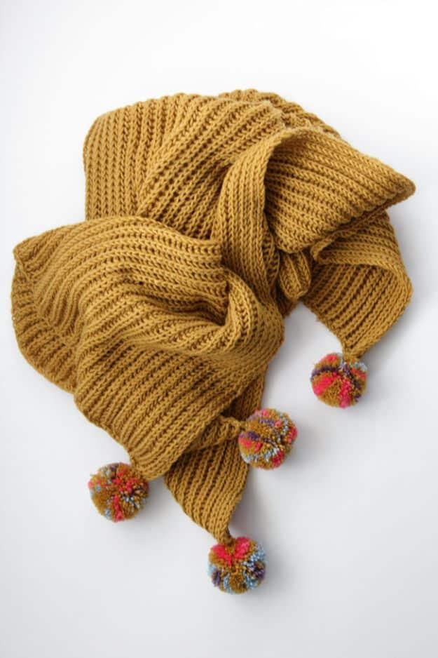 Mustard gold fisherman's rib baby blanket bunched to show its deep texture, with small colorful corner pompoms