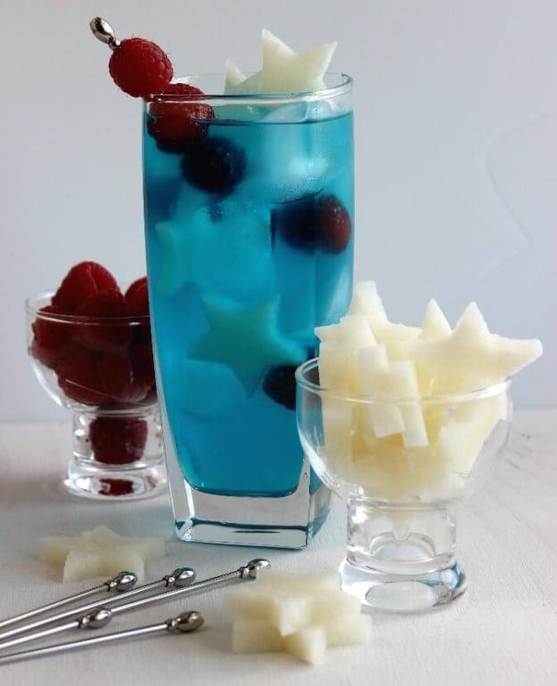 4th of July party idea: a patriotic passion cocktail mixed with stars and raspberries floating inside