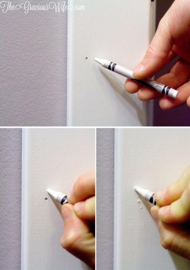 Hand filling nail holes in white trim with a crayon, shown in three close up photos on a pale lilac wall