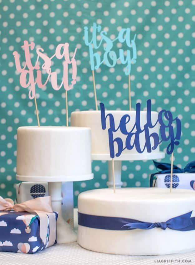 DIY baby shower decoration cake toppers reading it's a girl, it's a boy and hello baby in pink and blue cut card stock