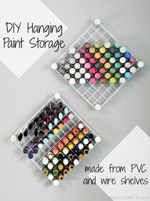 Two wall racks of craft paint bottles stored nozzle down in a grid, built from wire shelves and PVC pipe sections