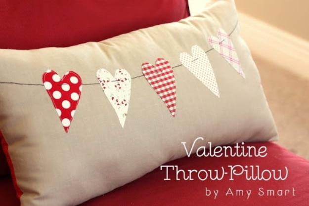 Neutral throw pillow with a pink fabric heart on the front sitting on a sofa as Valentine's Day decor