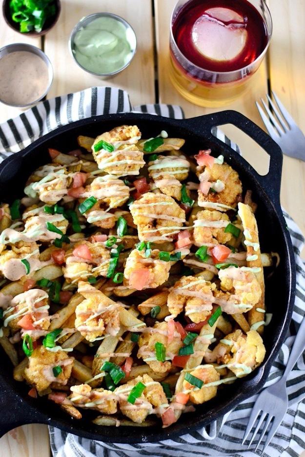 Shrimp po boy loaded fries piled with fried shrimp, remoulade and cool avocado sour cream on a sheet pan