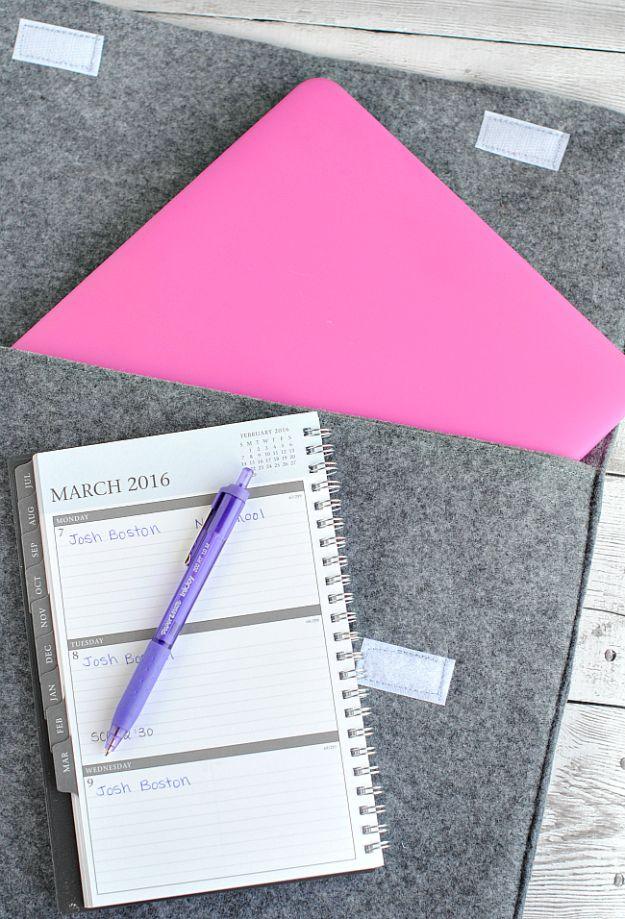 Ten minute laptop sleeve sewn from grey felt with a pink felt flap folded back, lying beside a spiral notebook and a pen