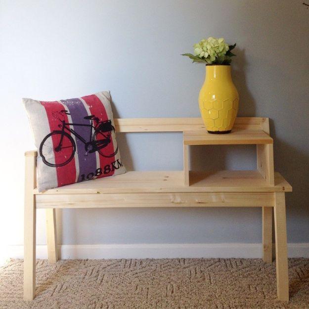Raw pine telephone bench with a seat, one armrest and a stepped side table holding a yellow vase and a bicycle cushion