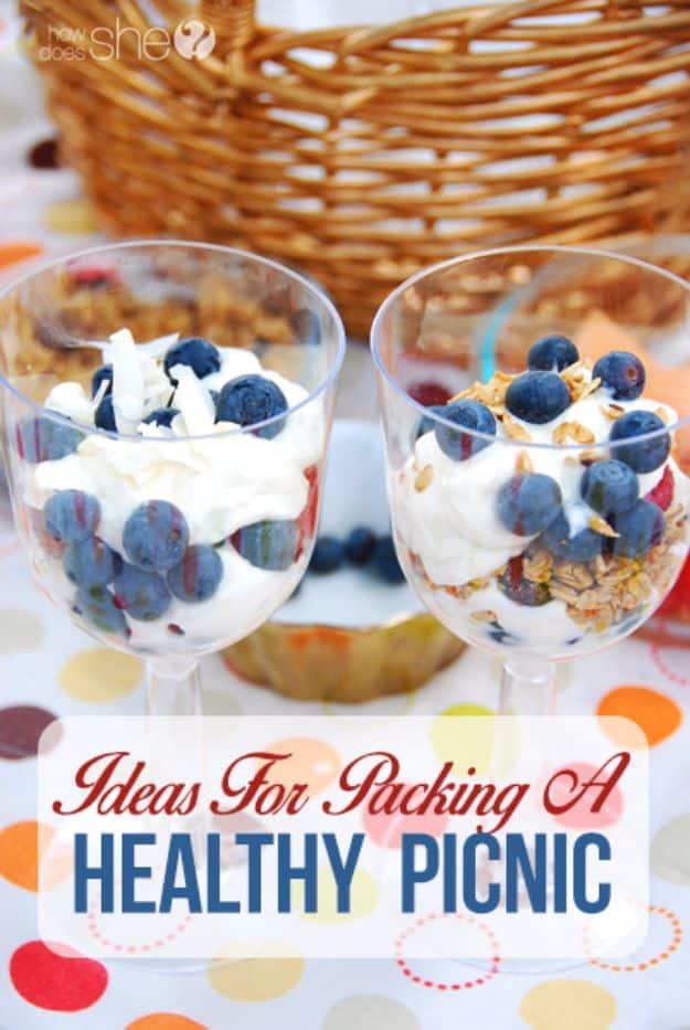 Pack a healthy picnic, two Greek yogurt parfaits layered with blueberries and granola in front of a wicker basket
