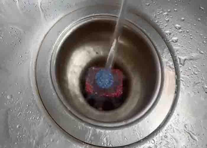 Pouring hot water in the drain with dishwashing tab