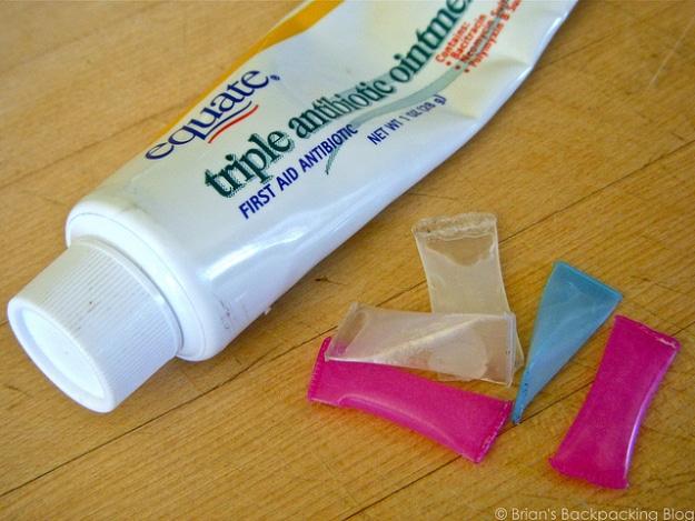 DIY single use antibiotic packs, five sealed drinking straw packets beside a triple antibiotic ointment tube