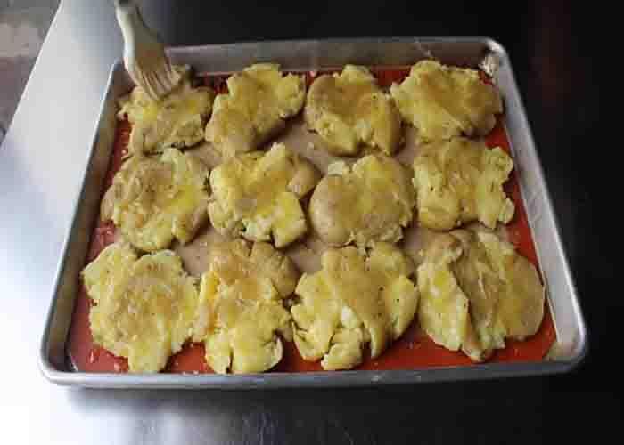 Brushing the smashed potatoes with infused butter