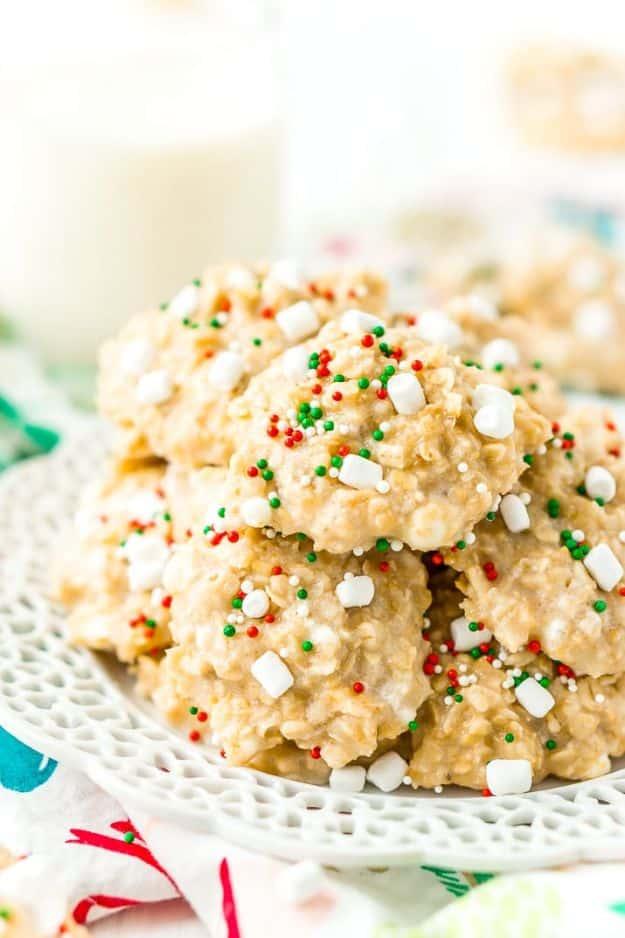 White hot chocolate no bake cookies with mini marshmallows and red and green sprinkles beside a milk glass