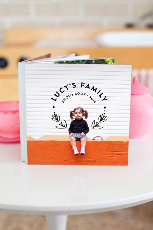 Square white photo board book standing open on a table, its cover a printed photo of a toddler on an orange bench