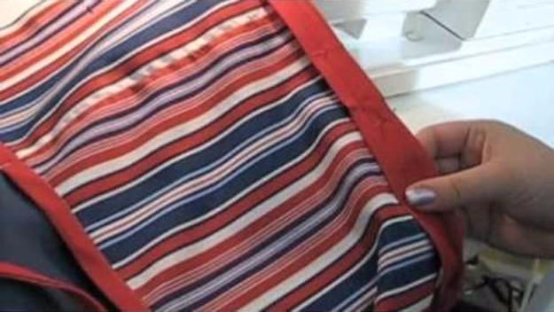 DIY bedside organizer in red white and blue striped fabric, a sewn pocket caddy held up beside a sewing machine