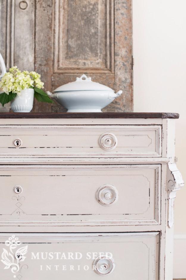 Cream painted dresser distressed along the drawer edges and around the hardware, styled with a white tureen and hydrangeas