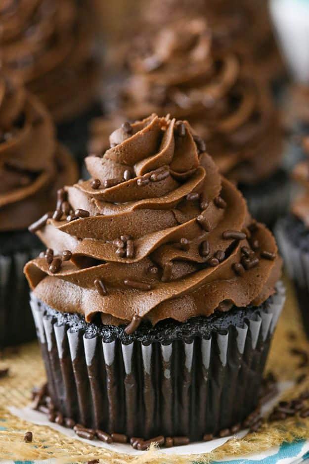 Moist chocolate cupcake piped high with fudgy chocolate buttercream and chocolate sprinkles on a gold doily