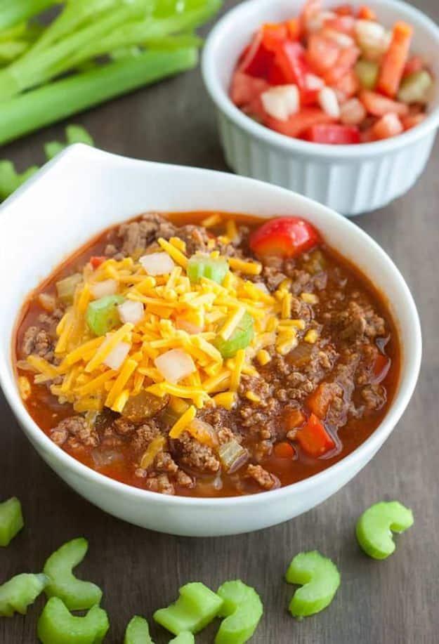 Low carb chili in a white bowl with shredded cheddar beside celery sticks and a dish of chopped pico