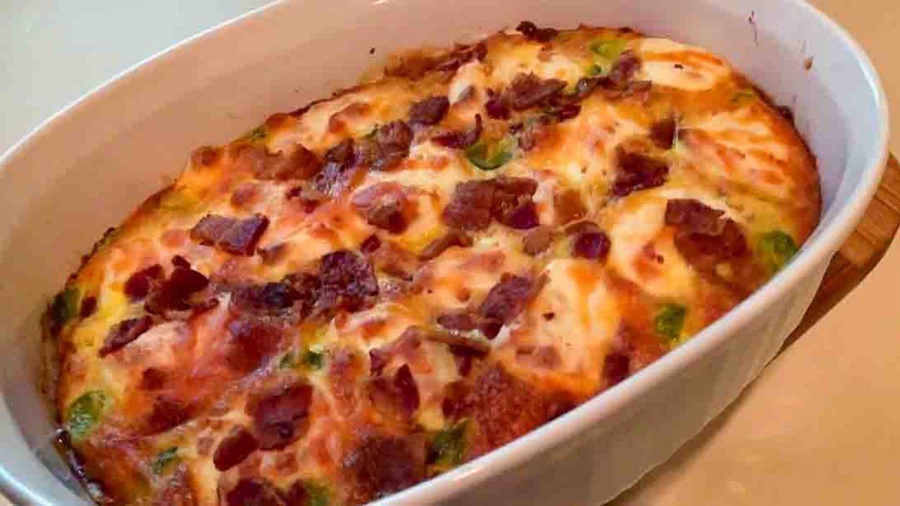 Keto cheeseburger casserole baked golden with bacon and pickle pieces on top in a white oval baking dish