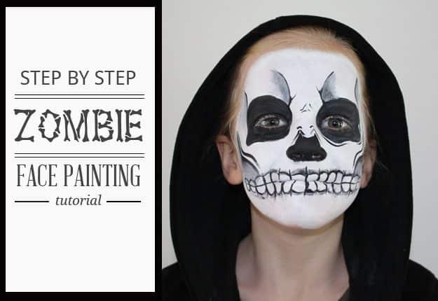 Zombie face paint with a white skull base, black eye sockets, a darkened nose and teeth painted over the lips