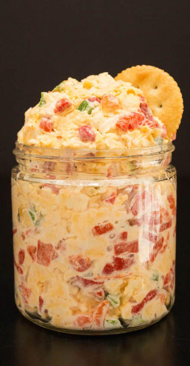 Best pimiento cheese packed into a glass jar, orange spread flecked with red pimento, a cracker tucked in