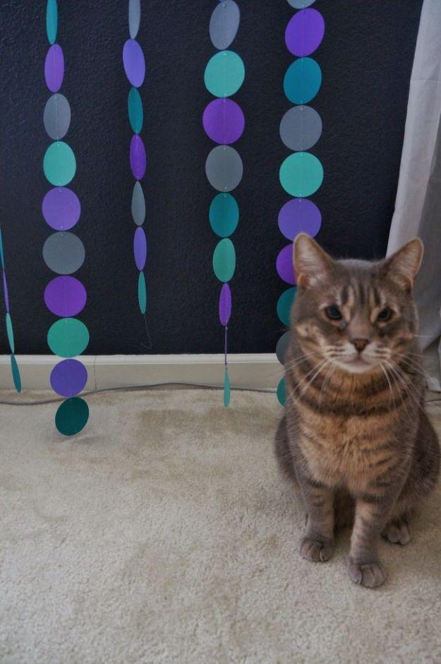 DIY baby shower decoration circle garland in teal purple and grey paper circles on fishing line against a dark wall
