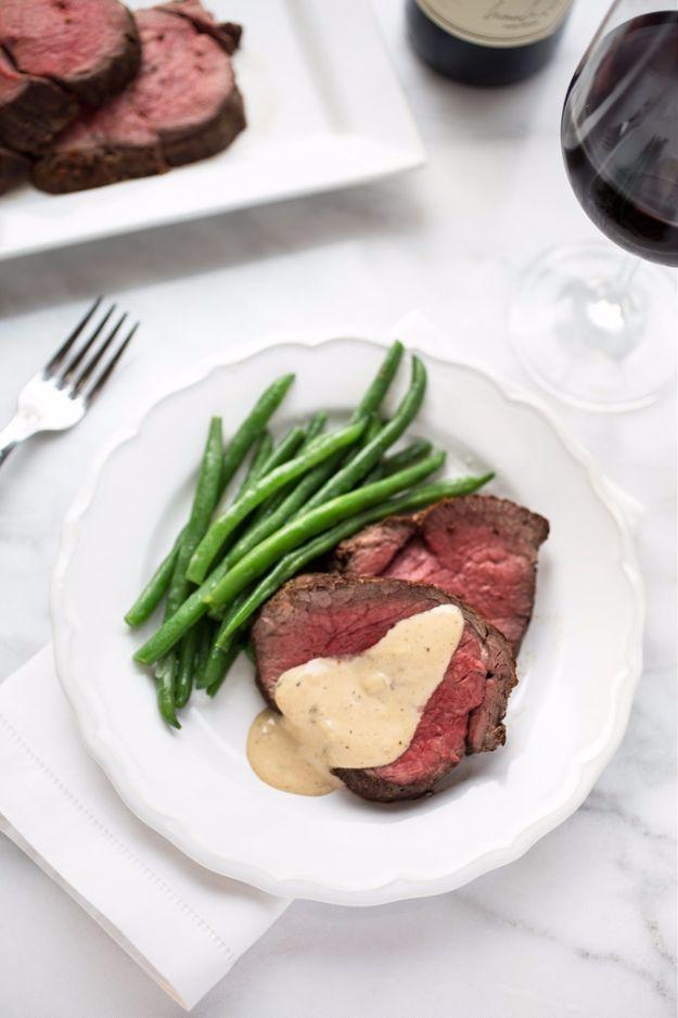 Beef tenderloin with cognac cream sauce, pink sliced beef on a white plate with green beans and pale sauce