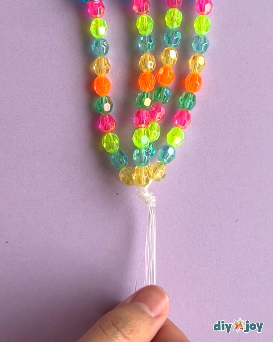 DIY home decor idea, a handmade beaded hanger holding a glowing candle jar above a table for a cozy evening