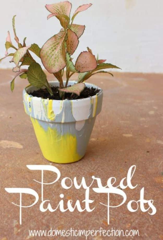 Terracotta pot with white, gray and yellow paint poured down the sides in stripes, holding a small plant