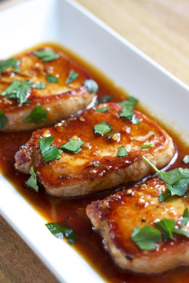 Honey garlic pork chops glazed until glossy and dark, garnished with chopped parsley in a white baking dish